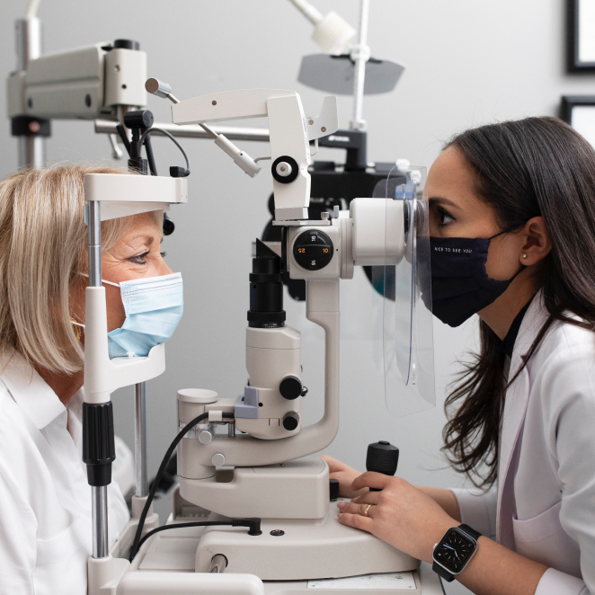 Optometrist viewing a patient's eye through a slit lamp microscope