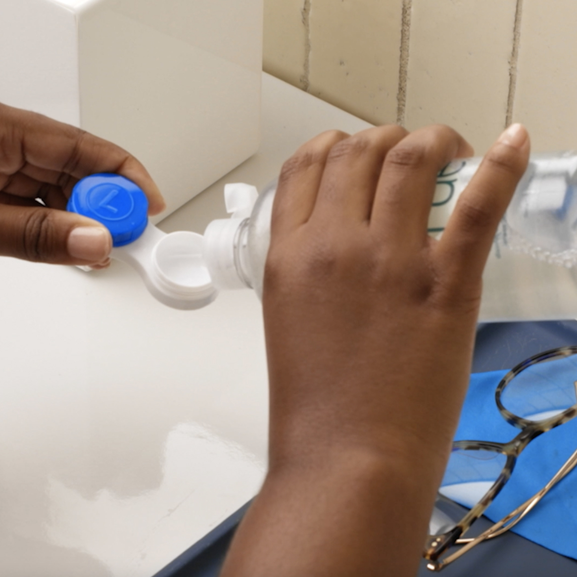 A person filling a contact lens storage case with solution