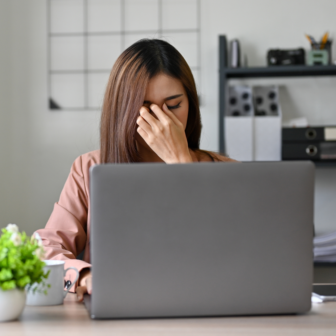 A woman experiencing eye pain while sitting at her laptop