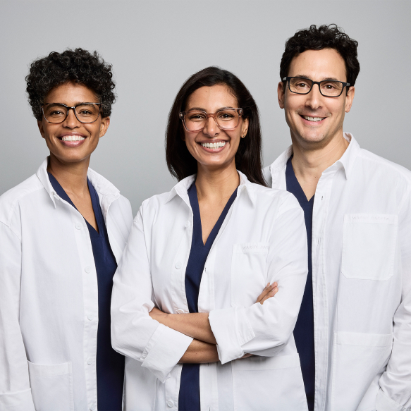 Three ophthalmologists in white lab coats smiling