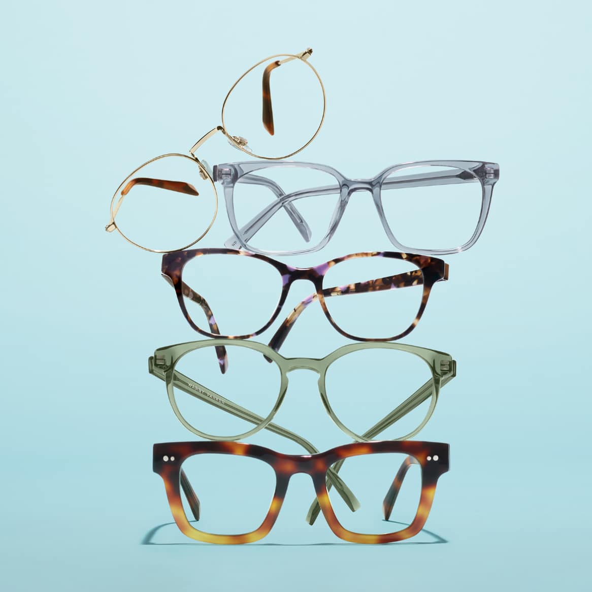 Five colorful glasses frames stacked on a blue surface
